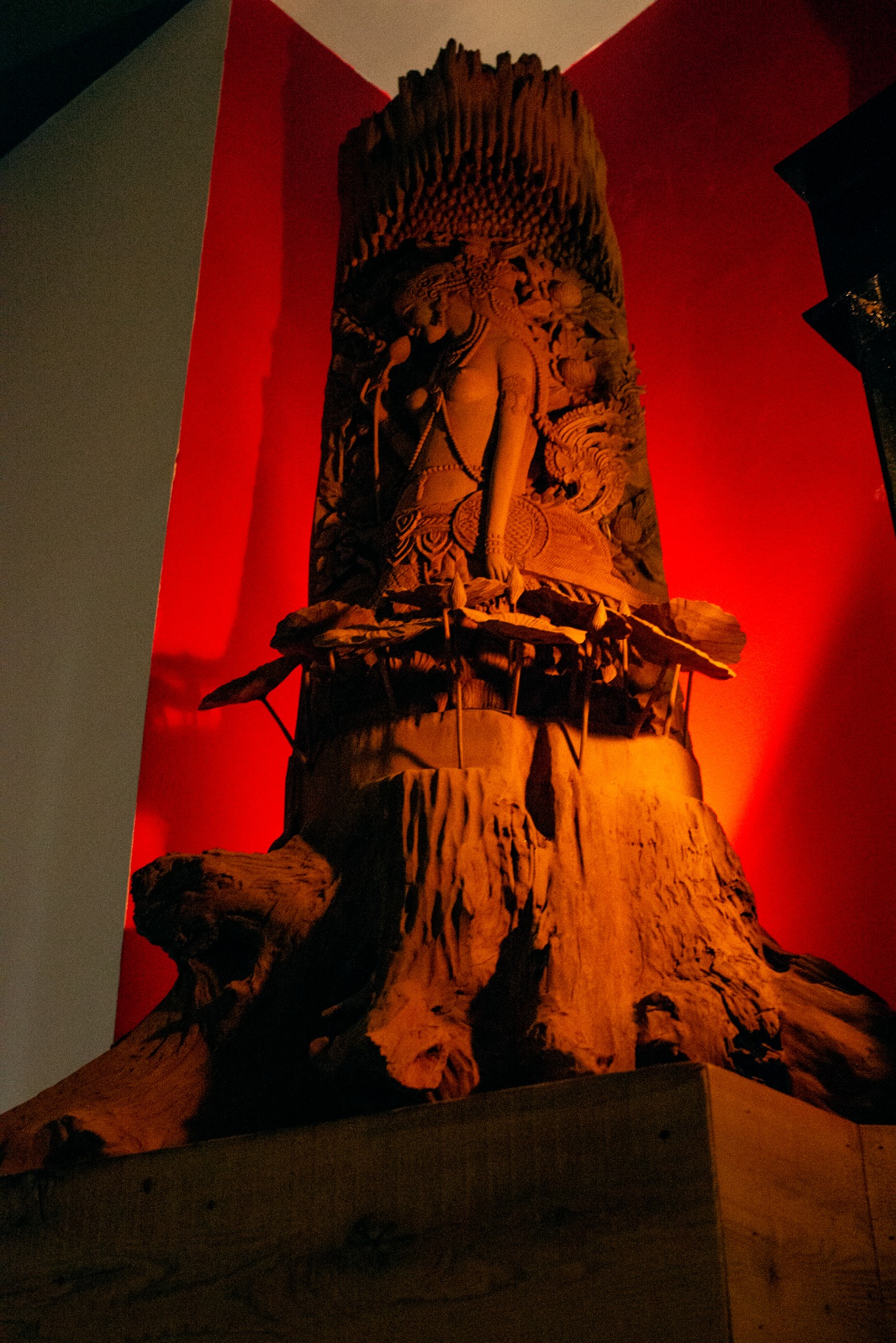 Sculptural Thai artwork illuminated against a deep red wall at Chatayee Thai